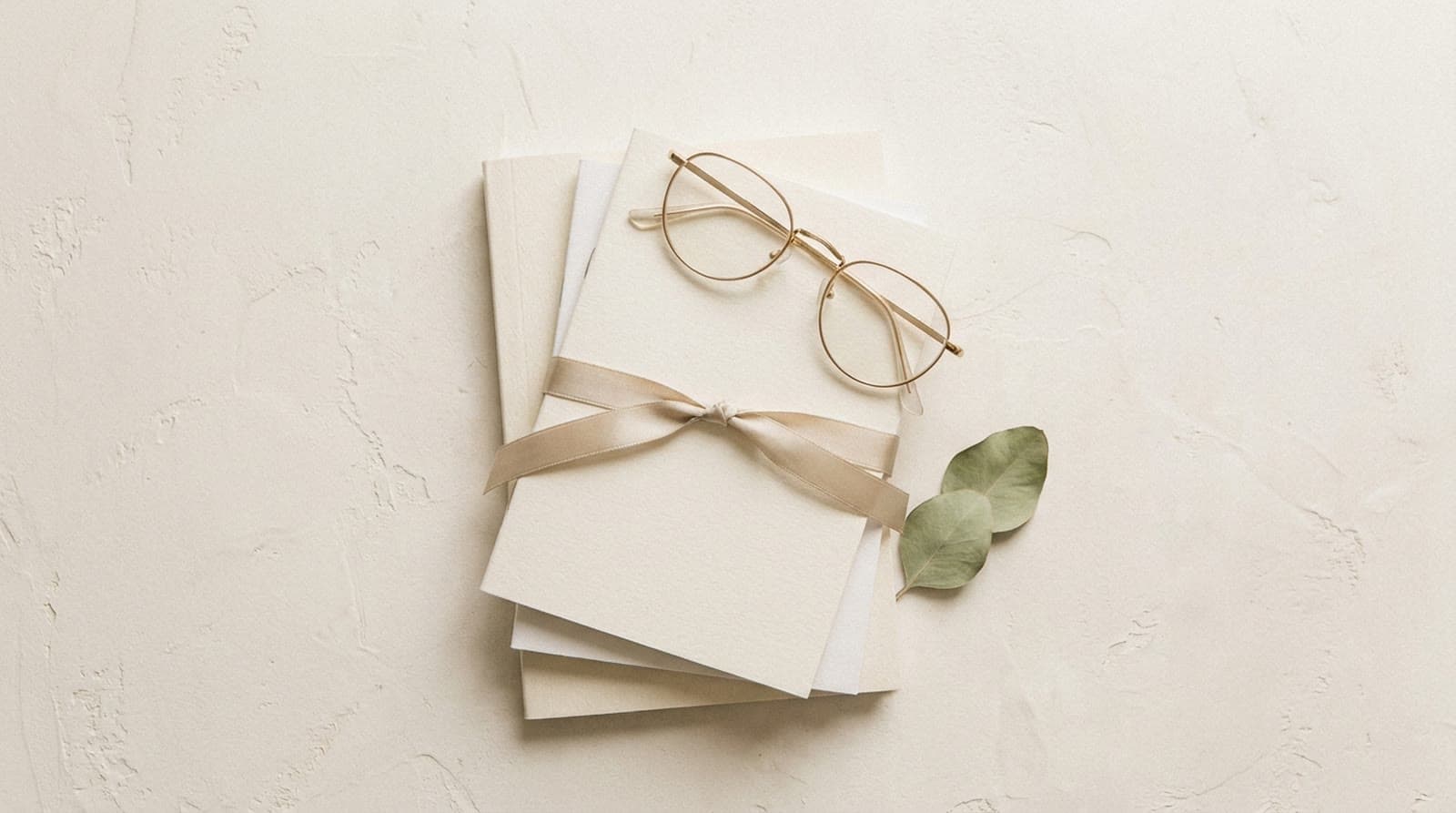 Stack of blank journals and reading glasses in soft daylight